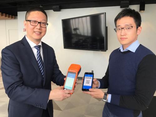 中国侨网River Pay公司创办人之一的郑莱恩(右)与ChinaPro行销公司总裁佟忠君(左)展示中国移动支付的付款流程。(美国《世界日报》/黄惠玲 摄)